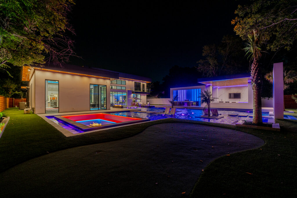 sunken in fireplace with waterfalls next to modern design pool in backyard of event venue rental